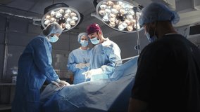 A surgical team, including doctors and nurses, are in an operating room performing a medical procedure. Surgeons in Operating Room - Powered by Shutterstock - Get 15% off with code: PIKWIZARD15