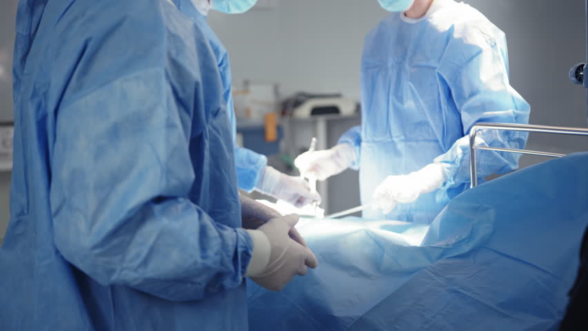 A Middle Eastern surgeon in a surgical gown after completing an operation with his colleagues in the operating room. Surgical team in the operating room. Surgical Team in Operating Room - Powered by Shutterstock - Get 15% off with code: PIKWIZARD15