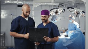 A team of medical professionals, including surgeons, examine an X-ray during a surgical procedure in a modern operating room. Surgical Team Discussing in Operating Room - Powered by Shutterstock - Get 15% off with code: PIKWIZARD15