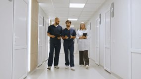 A diverse group of healthcare professionals, including doctors and nurses, walk and collaborate in a hospital hallway setting, engaged in a discussion. Medical Team Discussing in Hospital - Powered by Shutterstock - Get 15% off with code: PIKWIZARD15