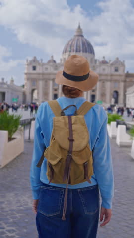  A girl tourist in a hat and with a backpack walks along as she admires the iconic St. Peters Square in Vatican City, Italy, 29.04.2025