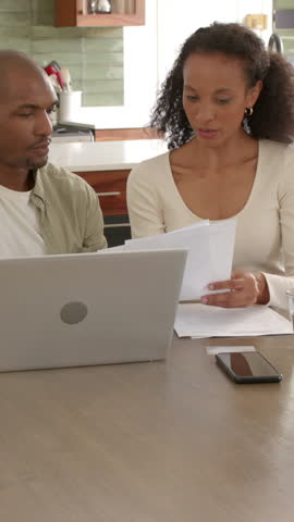 Vertical video: Spotting error on sheet, couple checking smartphone, leaning to laptop discussion. Collaboration, analysis, productivity, modern, communication, focus, vertical video