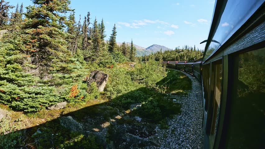 White Pass route train ride between Skagway Alaska and Whitehorse Yukon Canada. Beautiful sunny day with white clouds and blue sky