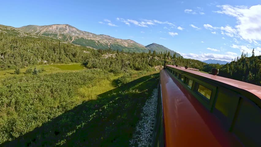 Alaska wilderness from White Pass and Yukon railroad train ride between Skagway Alaska and Whitehorse Yukon Canada. Beautiful sunny day with white clouds and blue sky