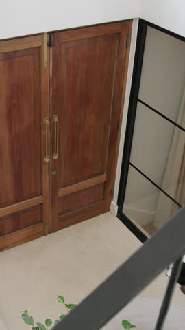 Vertical video: African American man using tablet opening doors in foyer, guiding clients upstairs. Technology, hospitality, modern, professionalism, architecture, welcoming, vertical video