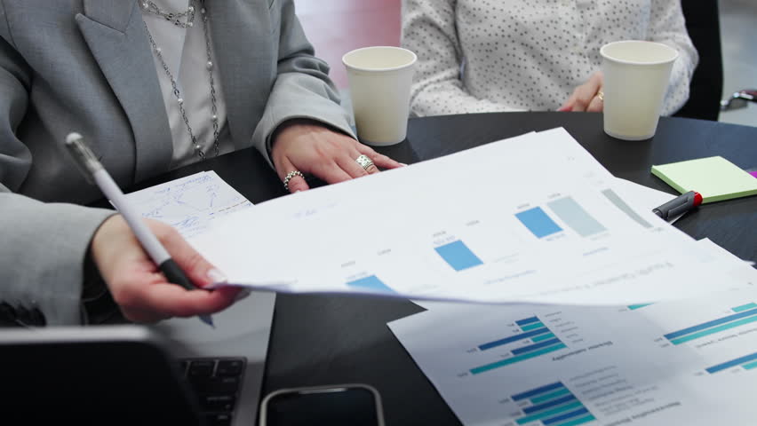 Closeup of business meeting table with analytics documents and hands writing notes during strategic planning session
