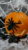 A small black spider crawls on a pumpkin with a white web with flashing lights, the concept of the Halloween holiday - Powered by Shutterstock - Get 15% off with code: PIKWIZARD15