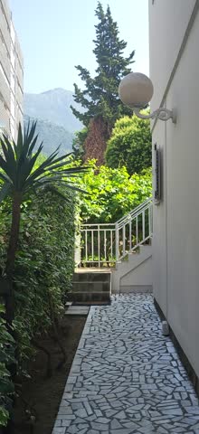 Residential buildings nestled in lush green hills with mountains in the background, showcasing the suburban landscape of Budva, Montenegro.