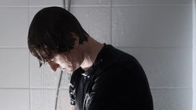 Bows his head under running shower water student in wet black shirt showing exhaustion sadness and deep emotional struggle - Powered by Shutterstock - Get 15% off with code: PIKWIZARD15