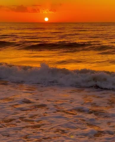 Beautiful sunset over the North Sea, scenic clouds, splashing waves, golden color. Ostend, Belgium. 