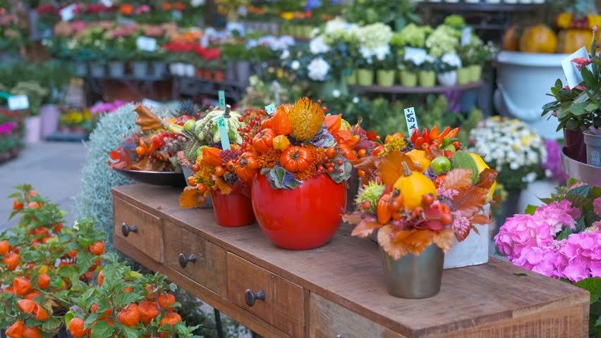 Flower shop displaying colorful autumn floral arrangements. Autumn flower arrangements on a wooden table are showing pumpkins, berries and colorful flowers