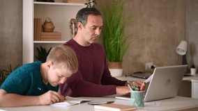 Father assisting his son with homework while using a laptop, demonstrating quality time and education - Powered by Shutterstock - Get 15% off with code: PIKWIZARD15