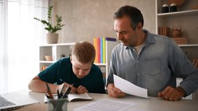 Caring father supporting son's learning, guiding through homework with patience and dedication at home desk - Powered by Shutterstock - Get 15% off with code: PIKWIZARD15