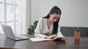 Young asian businesswoman sitting at desk and using calculator while taking notes - Powered by Shutterstock - Get 15% off with code: PIKWIZARD15