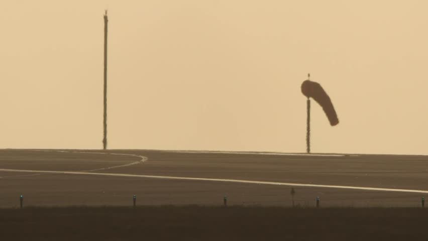 A windsock stands on the edge of the runway during calm morning conditions at Jersey Airport. — Editorial Use Only. Jersey, Channel Islands – September 1, 2025.