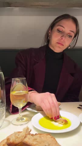 Young woman dipping bread in olive oil at a italian restaurant table