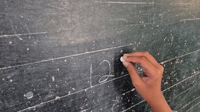 A female elementary school student is writing numbers on a blackboard with chalk. - Powered by Shutterstock - Get 15% off with code: PIKWIZARD15