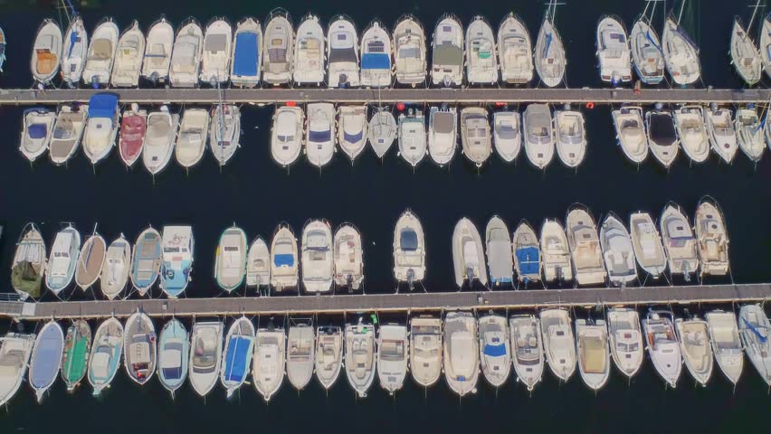 An aerial drone shot captures a vibrant marina in Marseille, France, showcasing numerous boats neatly docked along the piers.