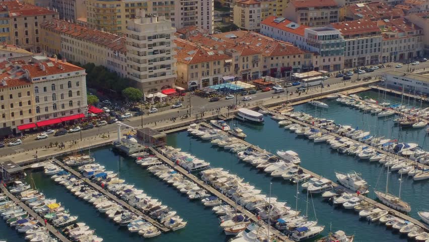 aerial perspective captures the bustling Vieux-Port of Marseille, France, showcasing rows of luxurious yachts and boats moored in the marina, framed by the historic cityscape and vibrant waterfront bu