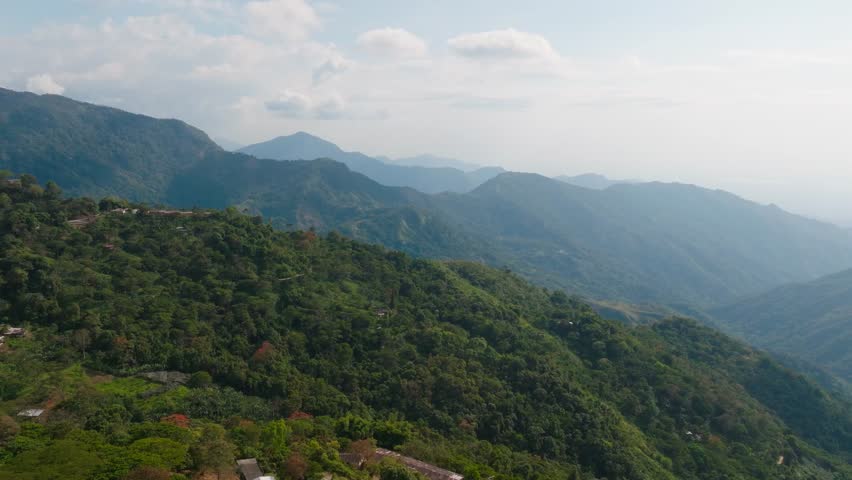 Drone view of the rolling hills of Sierra Nevada de Santa Marta near Minca, Colombia, covered in lush tropical jungle and mist, with dramatic mountain scenery