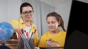 Teacher tutoring child at desk with laptop globe and pencil cup while student studies and smiles during homeschooling session study learning education tutor teacher student laptop globe family book - Powered by Shutterstock - Get 15% off with code: PIKWIZARD15