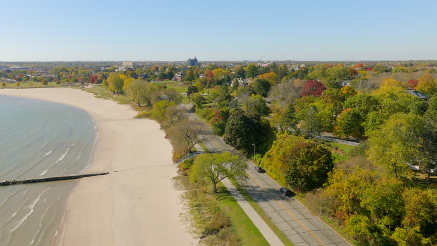 Drone aerial over a road along Lake Michigan in Sheboygan, Wisconsin with houses, trees, and a pleasant neighborhood view on a colorful autumn day.
