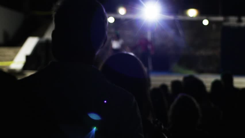Silhouettes of people in the concert hall in front of the stage waiting for the performance