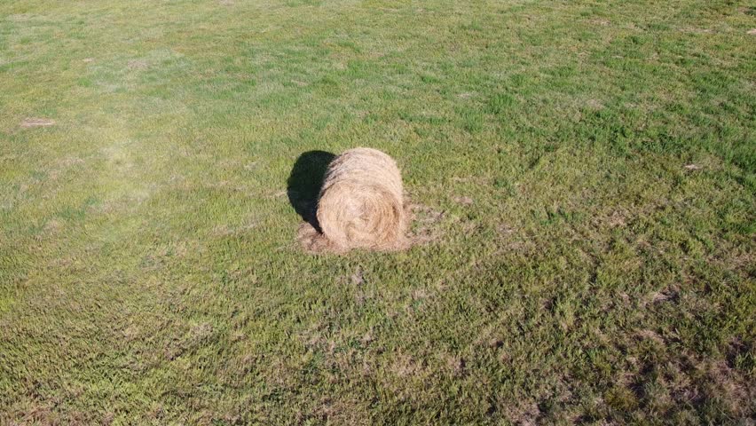 Aerial Video Circling Around Round Hay Bale in Countryside Field