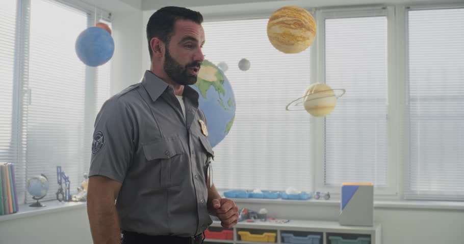 Male TSA Security Officer in Uniform Giving Lecture, Explaining Safety Rules to Young Students in Colorful Elementary School Classroom. Basic Information for Kids About Discipline, Law, Responsibility