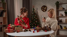 Two women are enjoying the holiday spirit as they prepare for Christmas. They wrap handmade gifts and take photos with holiday decorations. - Powered by Shutterstock - Get 15% off with code: PIKWIZARD15