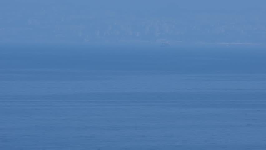 Humid weather on the Adriatic Sea. Beautiful landscape with calm a tranquil blue water surface and the block houses of Rijeka, Croatia in the background. View from the Krk Island.