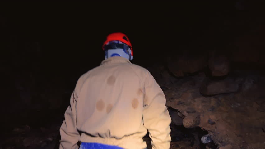 A speleologist explores a cave, illuminated by a headlamp. High quality 4k footage
