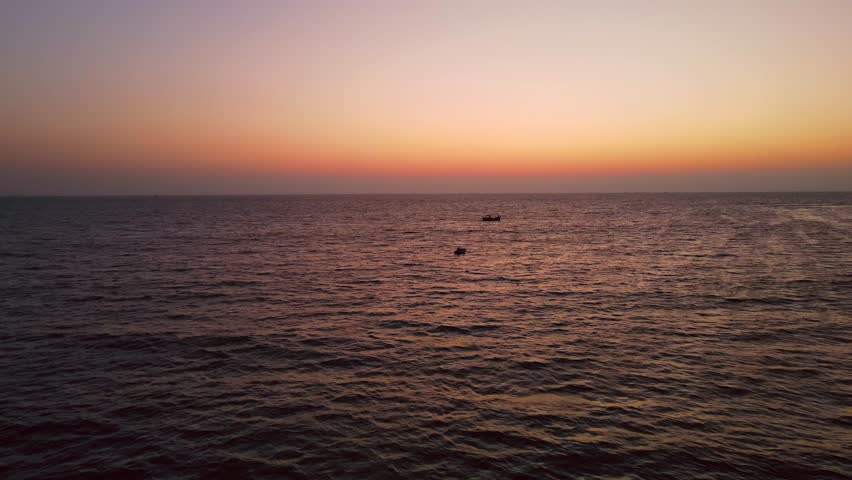 Aerial view of boats sailing on the sea under a gradient sky, creating a mesmerizing seascape with warm and cool tones, Karachi, Sindh, Pakistan.