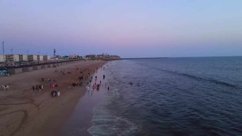 Aerial view of Clifton Beach as the waves crash against the sandy shore under a pastel sky, Karachi, Sindh, Pakistan.