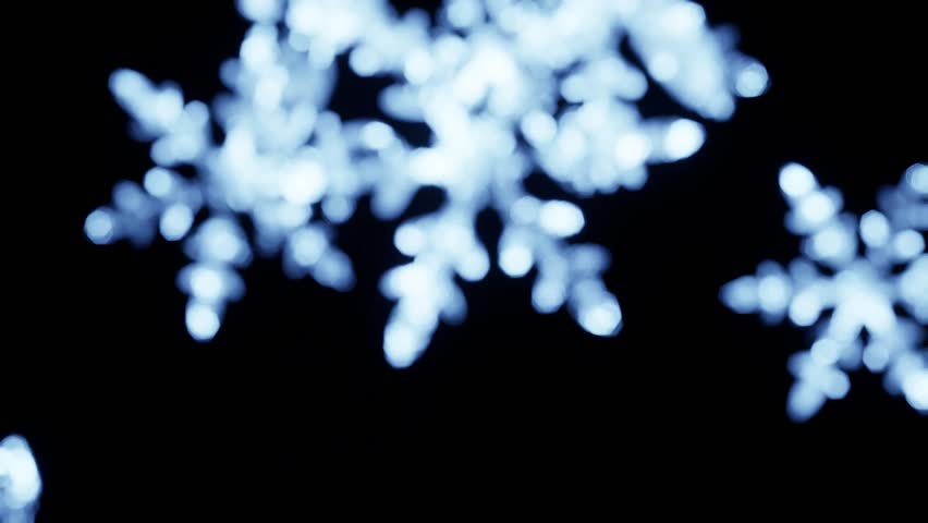 magical, soft-focus animation of a glowing blue snowflake on a dark background. Perfect for holiday greetings, winter christmas promos, and magical-themed video