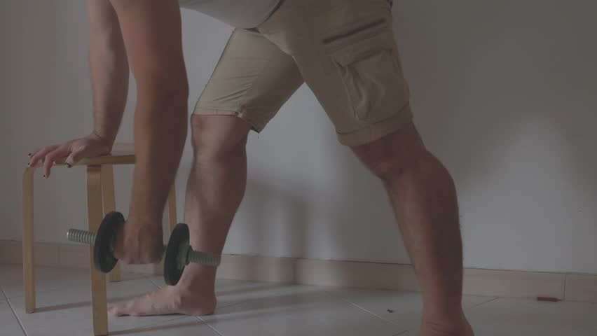 Man lifting dumbbell weights while leaning on stool