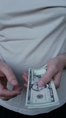 Closeup of man's hands counting dollar cash banknotes. Caucasian man calculates his income, salary, profit. Making money, success, wealth concept. Vertical video.