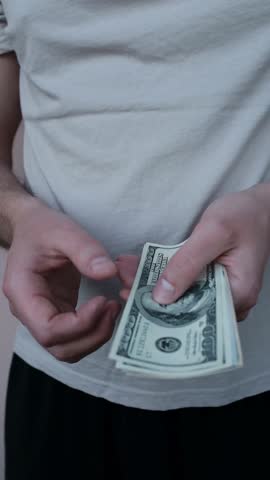 Closeup of man's hands counting dollar cash banknotes. Caucasian man calculates his income, salary, profit. Making money, success, wealth concept. Vertical video.