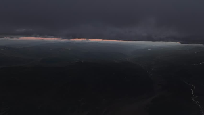 Twilight in the mountains. Aerial view of the countryside with rivers and lakes far below. Low key mountain evening landscape