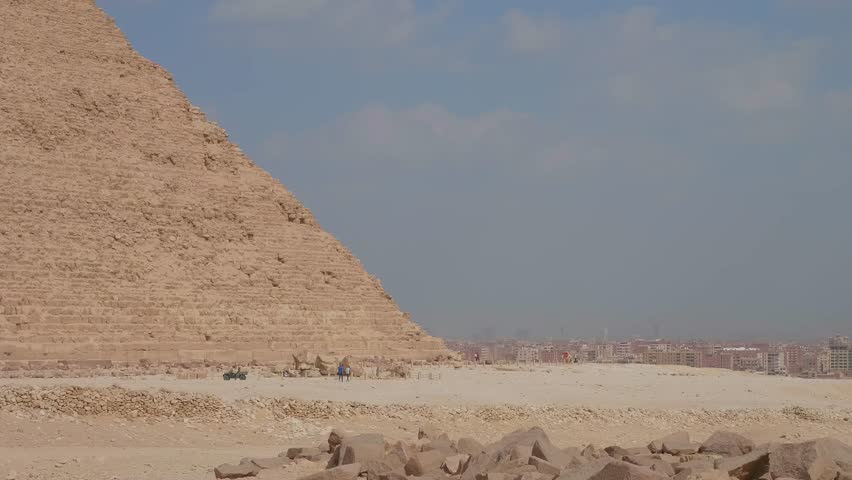 A wide shot capturing the majestic Pyramids of Giza, including the Great Pyramid, set against the vast desert landscape under a clear sky, showcasing the ancient wonders of Egypt.