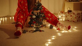 Woman in Santa Hat Sitting on Floor and Decorating Small Christmas Tree with Handmade Ornaments and Warm Lights. - Powered by Shutterstock - Get 15% off with code: PIKWIZARD15