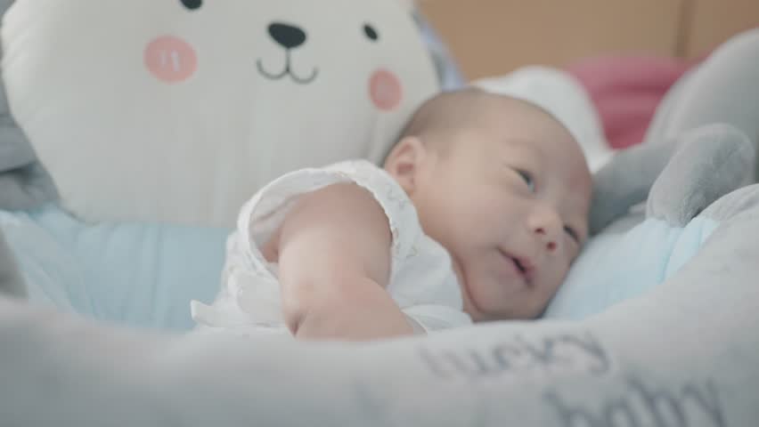A happy baby smiles and laughs in a soft, comfortable crib, surrounded by plush toys and a soothing environment. This image captures the pure joy and innocence of early childhood.