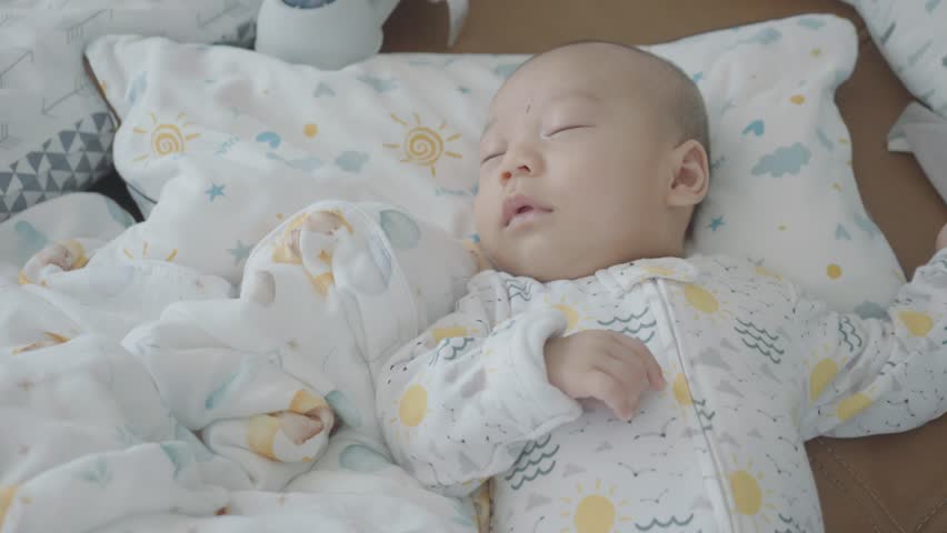 A serene image of a baby peacefully sleeping in a cozy crib surrounded by soft bedding and playful patterns. The scene invokes a sense of calm and warmth, perfect for conveying themes of innocence and