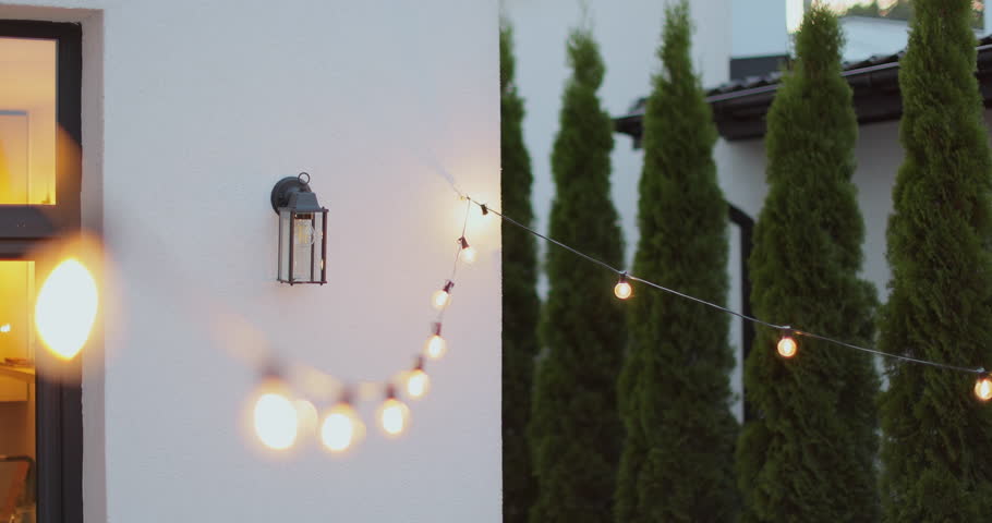 String lights hanging on line on outside house in backyard. Garden decoration. Party camping.