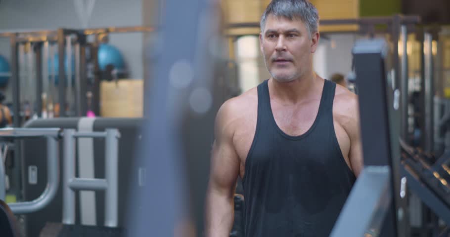 Gym workout. Bicep exercise. Middle aged Caucasian man trains his bicep muscles in the gym. Dedicated workout session with man performing bicep curls, aiming for improved arm strength.
