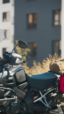A middle aged male biker in denim clothes puts on a helmet. Middle-aged biker in denim gear carefully puts on his helmet, preparing for a safe ride ahead.