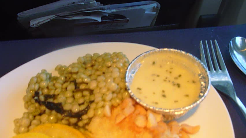 Flying in airplane, window seat panning shot to first class meal, point of view.