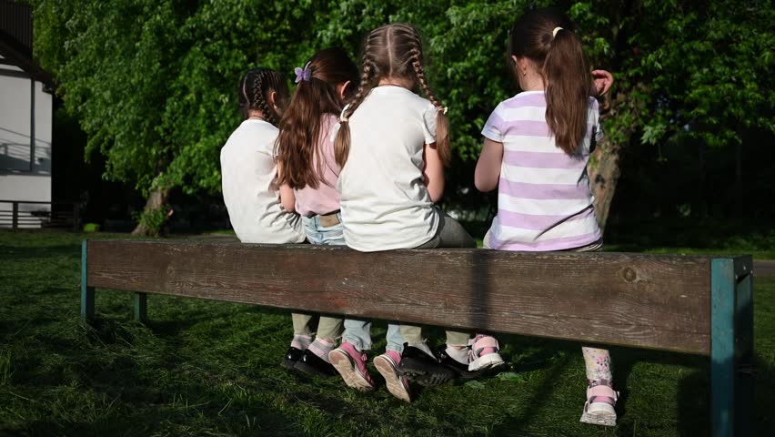 Four Young Girls Enjoying a Peaceful Afternoon Together on a Park Bench.