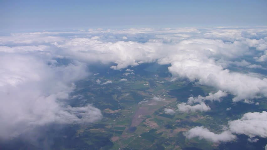 Flying in airplane over Pacific Northwest with clouds below and blue sky