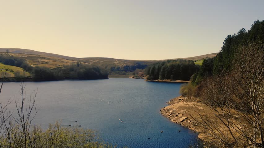 Lake and farmland in Peak District National Park blue sky landscape wide zoom drone aerial selective focus